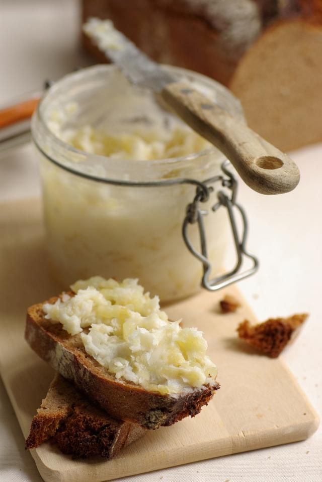 a piece of bread sitting on top of a cutting board next to a jar of cream