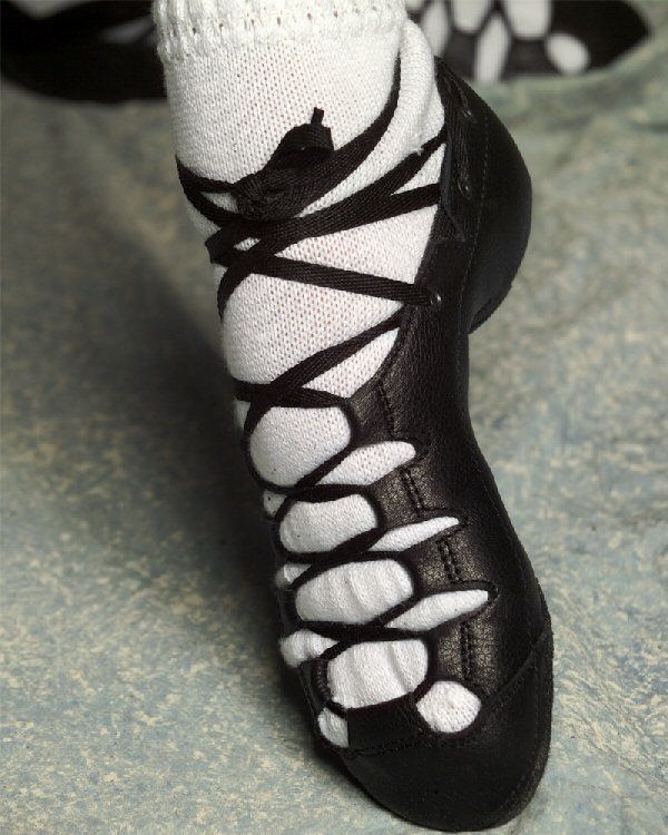 the feet of a person wearing black and white shoes with laces on them,