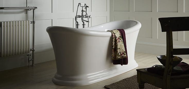 a white bath tub sitting on top of a hard wood floor next to a chair