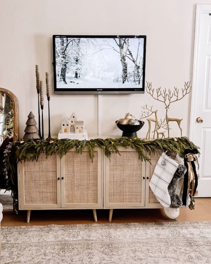 a living room with christmas decorations and a flat screen tv mounted above the entertainment center