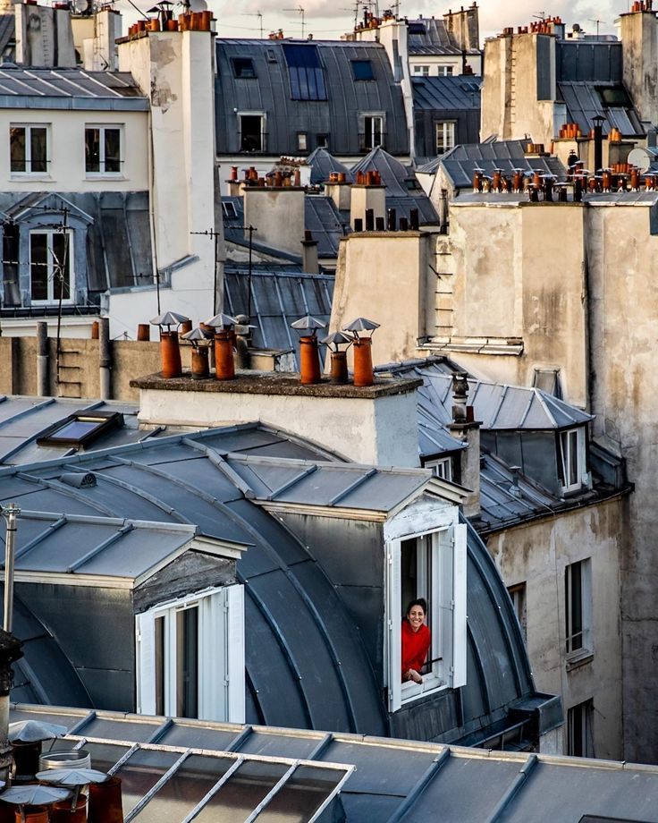 a person standing on the roof of a building looking out at rooftops and buildings