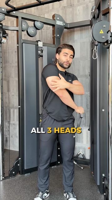 a man is standing in front of the gym machine with his arms crossed and looking at the camera