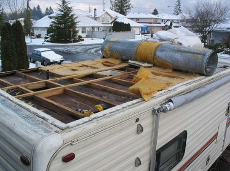 an old camper trailer is being worked on with wood and pipes attached to the roof