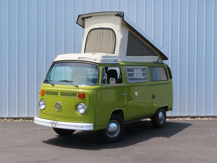 an old vw bus parked in front of a building with a roof tent on top