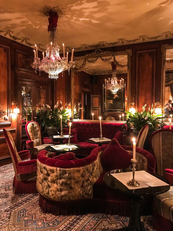 a living room filled with red couches and chairs next to a chandelier