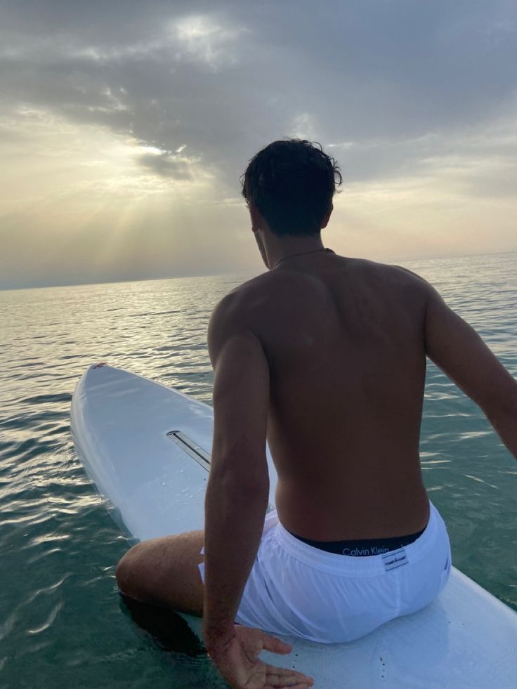 a man sitting on top of a surfboard in the ocean