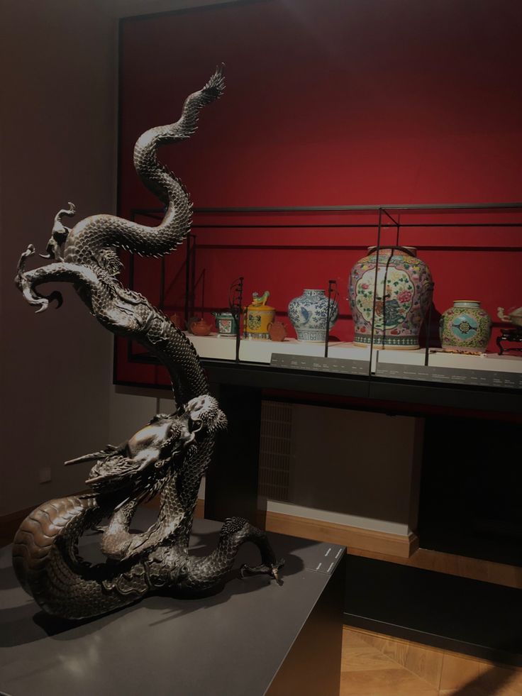 a dragon statue sitting on top of a table next to vases