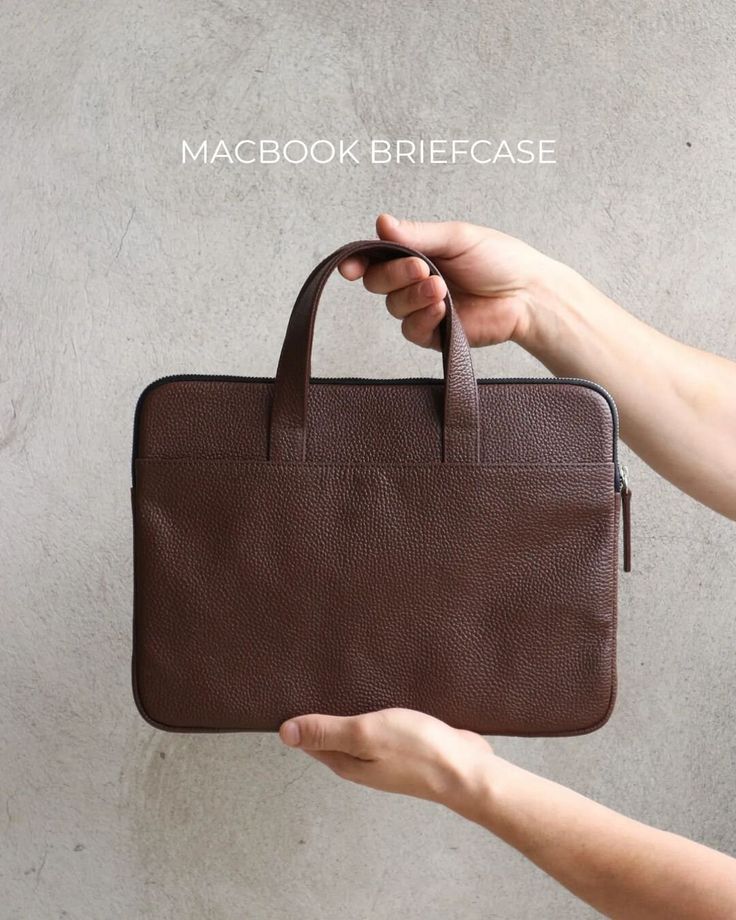 a person holding a brown briefcase in their hand with the text macbook brief case on it