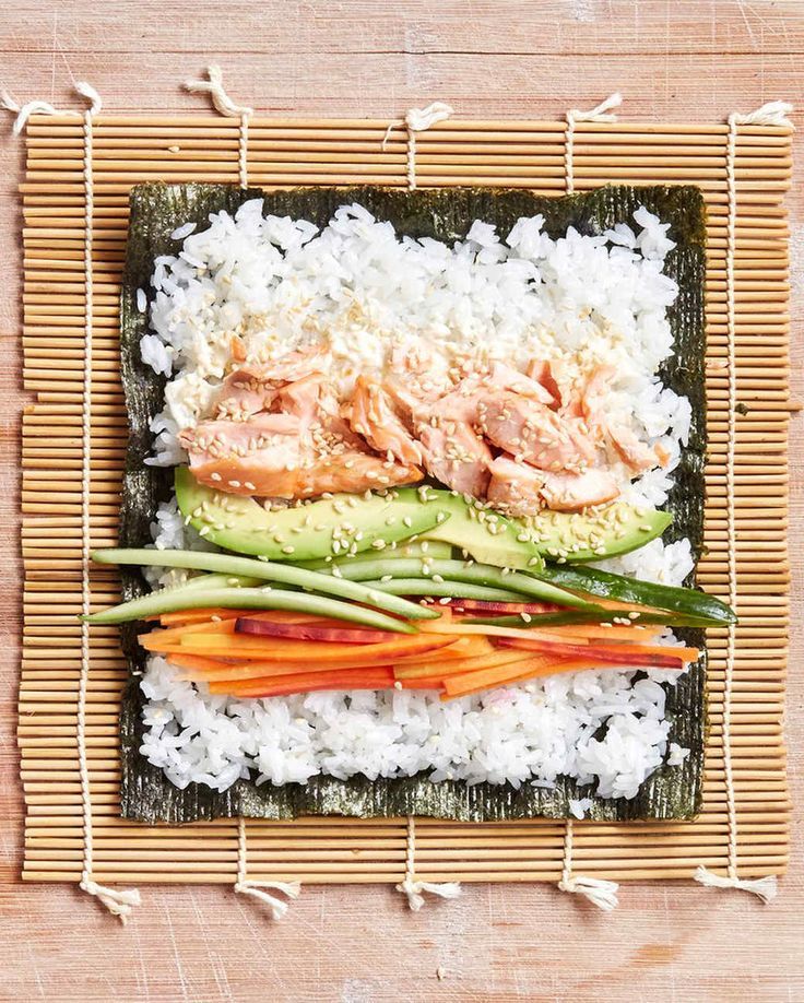 an overhead view of rice, carrots and salmon on a bamboo mat