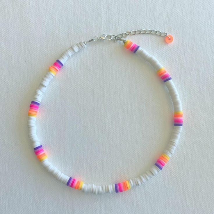 a bracelet with multicolored beads and a silver chain on a white surface,