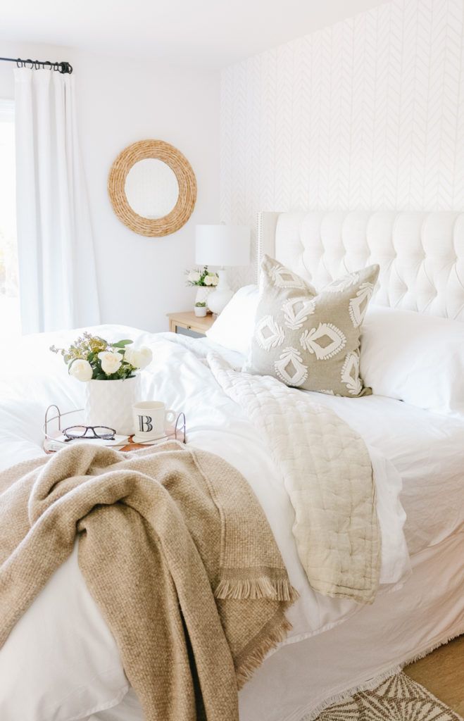 a bedroom with white bedding and pillows