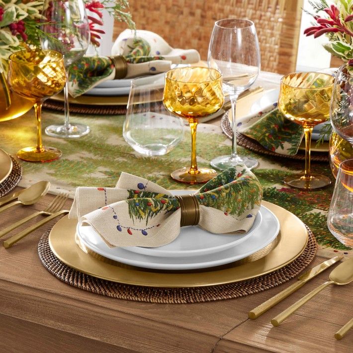 the table is set with gold and white plates, silverware, and wine glasses