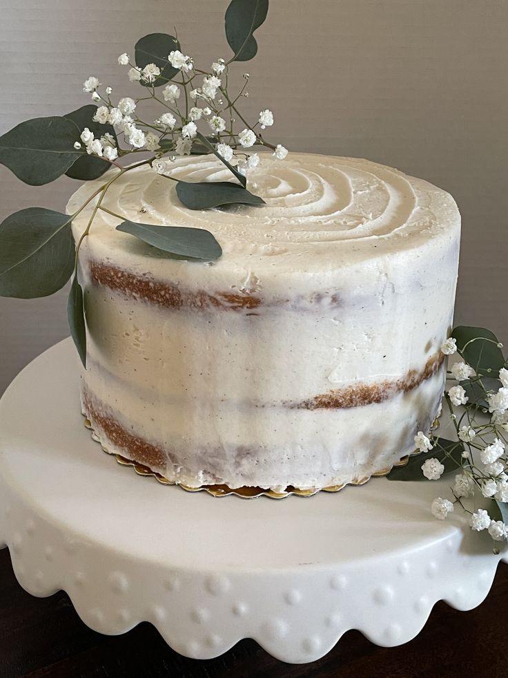 a cake with white frosting and greenery on top