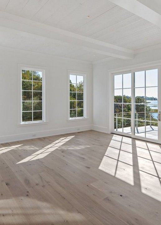 an empty room with three large windows overlooking the water