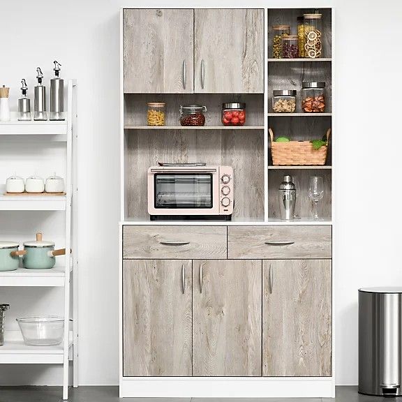 a microwave oven sitting on top of a wooden cabinet next to shelves filled with food