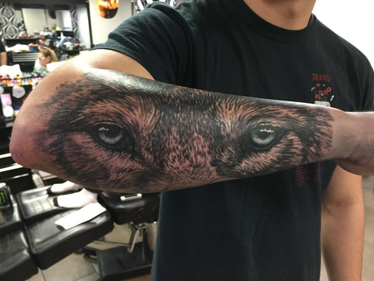 a man with a tattoo on his arm holding up a bear's head and eyes