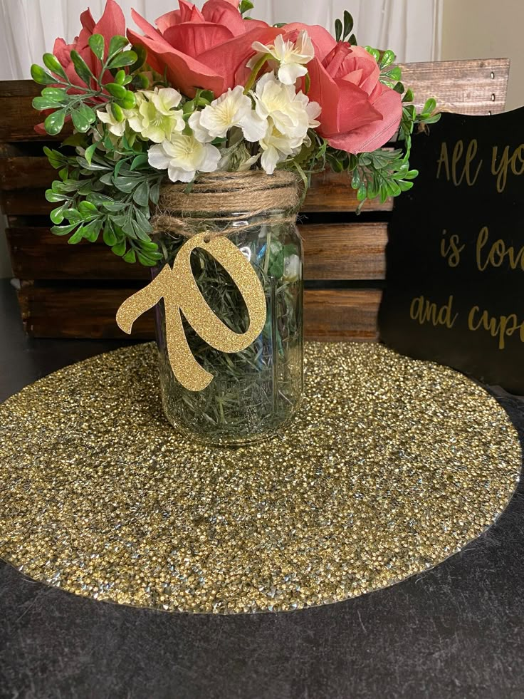 a mason jar filled with flowers sitting on top of a table next to a sign