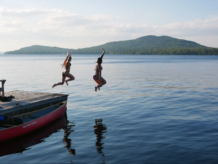 two people jumping into the water from a dock