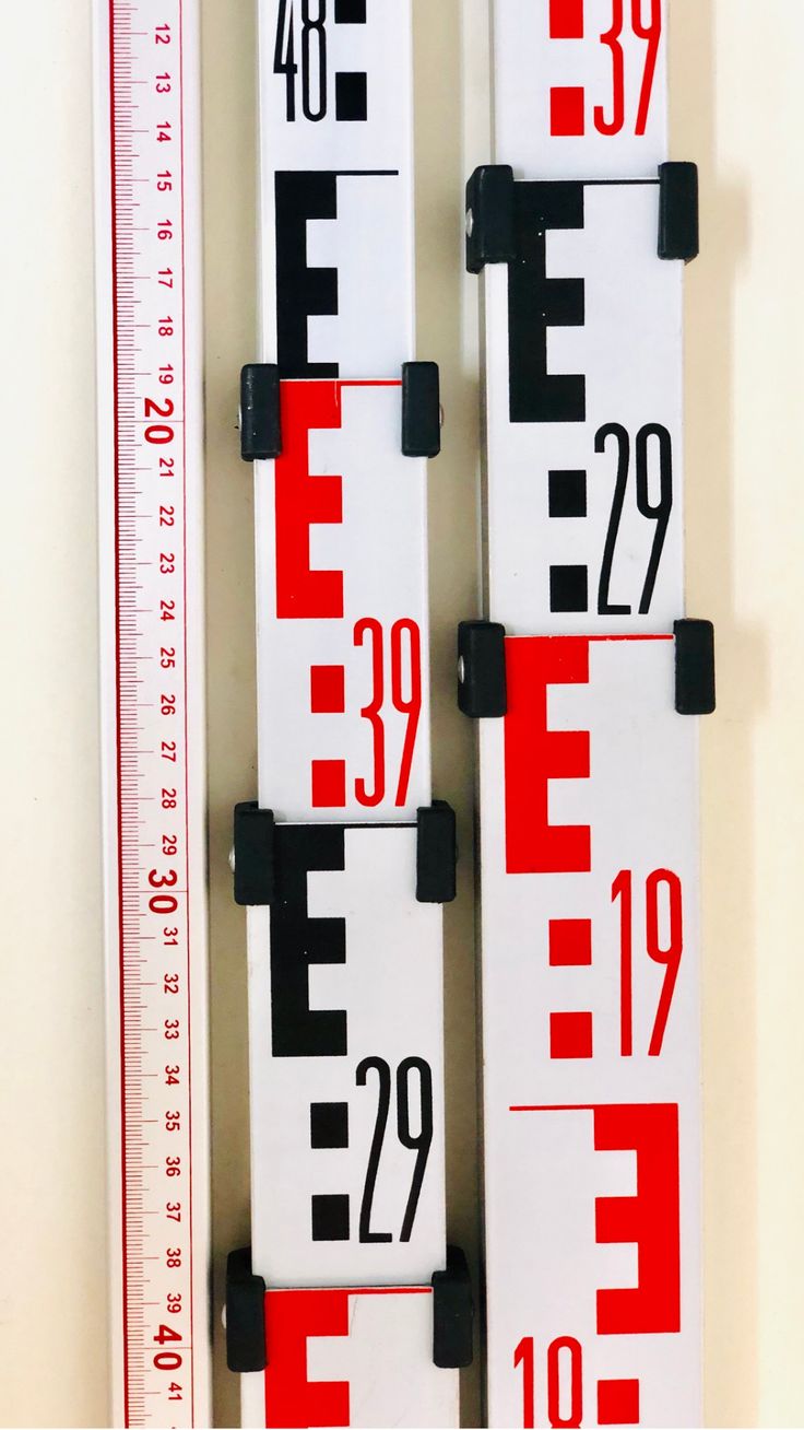 three red and white rulers are hanging on the wall next to a ruler with numbers