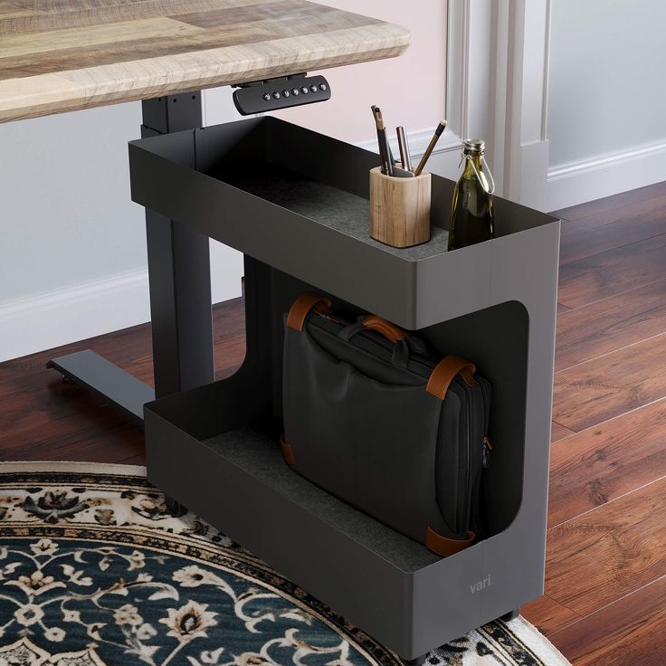 a black bag sitting on top of a wooden table next to a desk with a laptop