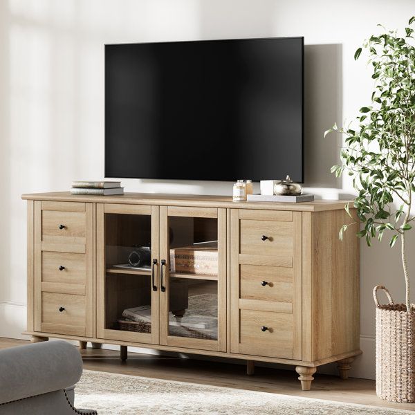 a large flat screen tv mounted on top of a wooden cabinet