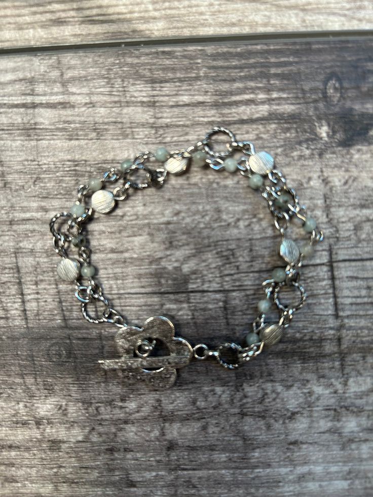 Sundance style Tian Shan Lan stone bracelet.  This lovely bracelet has two strands.  One is made of Tian Shan Lan 3mm round stones wire wrapped together. The second strand is made up of twisted metal loops, silver metal chain links and flat round bushed silver metal beads.  The stones are shades of pale green and grey.  A brushed metal flower toggle clasp completes the bracelet.    The bracelet is 7 3/4 inches in length. Silver Double Strand Bohemian Jewelry, Bohemian Silver Double Strand Jewelry, Adjustable Silver Bohemian Chain Bracelet, Bohemian Double Strand Silver Jewelry, Silver Double Strand Jewelry, Bohemian Silver Chain Bracelet, Nickel Free Silver Metal Rosary Bracelet, Nickel-free Silver Metal Rosary Bracelet, Nickel-free Metal Bohemian Chain Bracelet