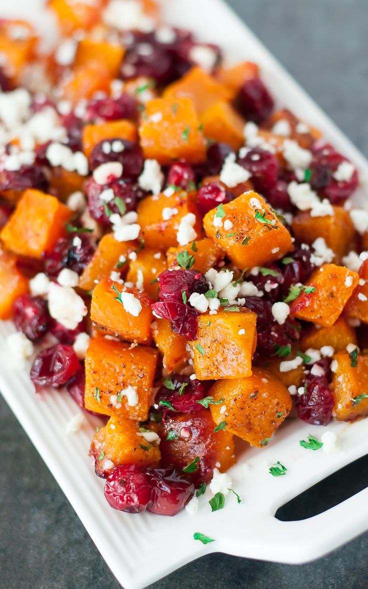 a white plate topped with carrots and cranberries covered in feta cheese