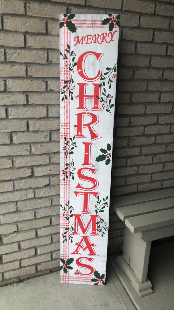 a merry christmas sign on the side of a brick wall next to a wooden bench