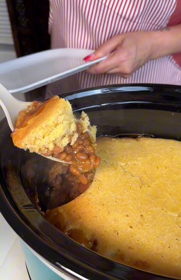 a person scooping some food out of a crock pot with a spatula