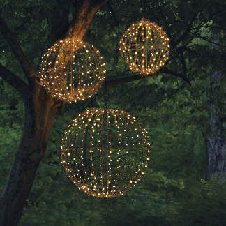 three lighted balls hanging from a tree in the woods