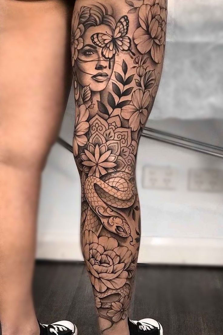 a woman's leg with flowers and a snake on the bottom half of it