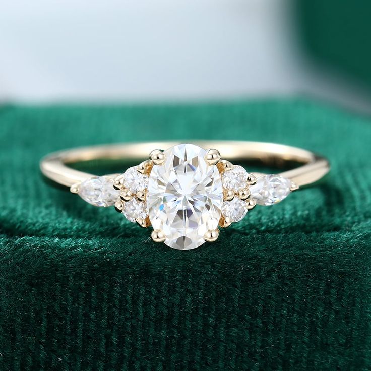 an engagement ring with three stones on it sitting on a green velvet cushioned box