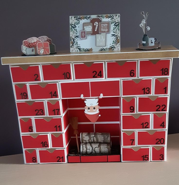 a red and white shelf with some christmas decorations on it's top, next to other items