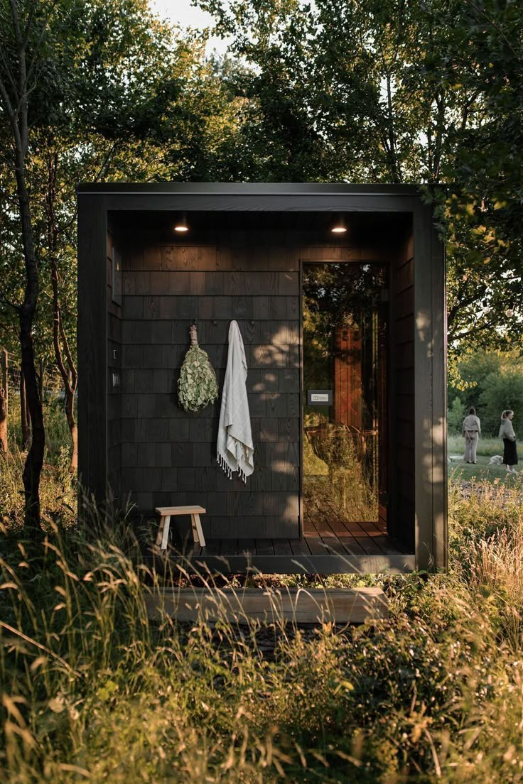 an outhouse in the woods with a towel hanging on it's door and a bench