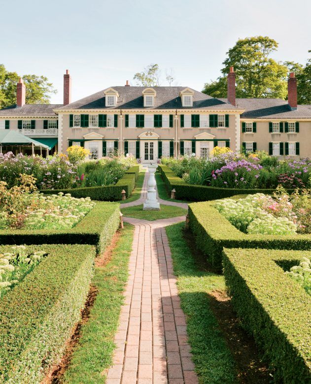 a large house surrounded by hedges and flowers