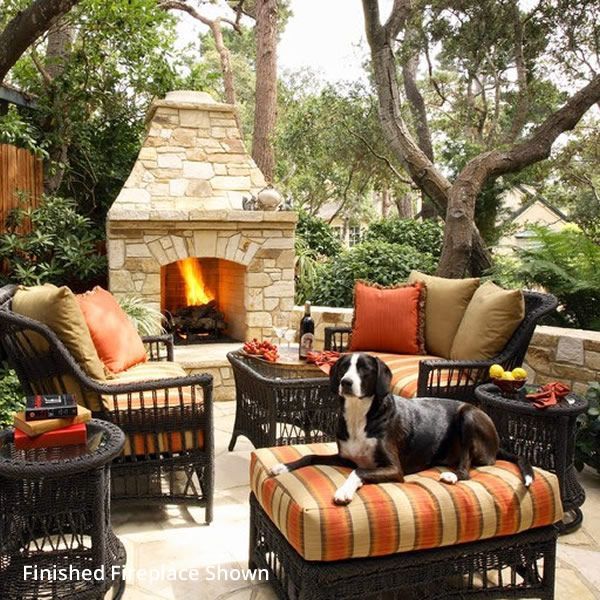 a dog sitting on top of a chair next to a fire place in a backyard