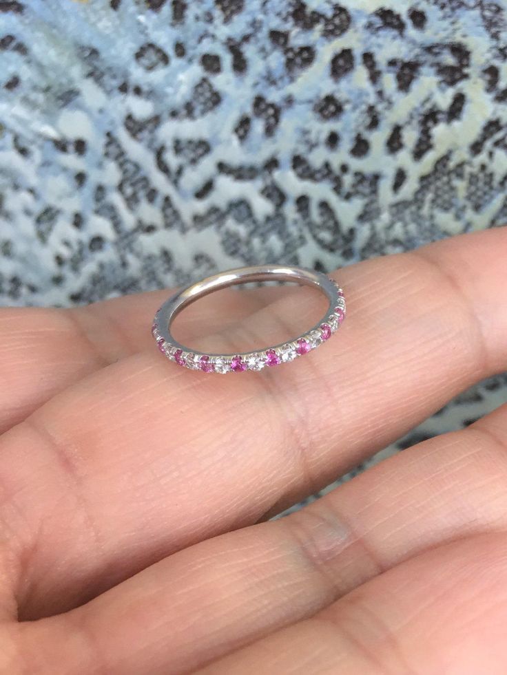 "Delicate White Gold Full Eternity Pave Band Ring with alternating Diamonds and Pink Sapphire Gemstones. Material: 14K White Gold Plating: Rhodium/ Platinum Family Finish: High Polished/ Shiny Fit: Comfort Fit/ Rounded Interior Width: 1.6mm Height: 1.6mm Setting: U Micro Pave Set Stone: Conflict Free Natural Diamonds Cut: Brilliant Clarity: VS Color: G-H Alternating Stone: Natural Pink Sapphire Stone Cut: Round Diamond Cut Quality: AAA Stone Size: 1.3mm Total Carat Weight: 0.48+ ct (varies by ri Pink Sapphire Eternity Band, Pink Diamond Half Eternity Band, Pink Half Eternity Diamond Band, White Gold Ruby Ring With Halo For Wedding, Pink Diamond Eternity Band For Anniversary, 14k White Gold Half Eternity Round Band, White Gold Half Eternity Promise Band, Wedding Rings With Diamond Cut Pink Sapphire, Pink Sapphire Stackable Ring For Wedding