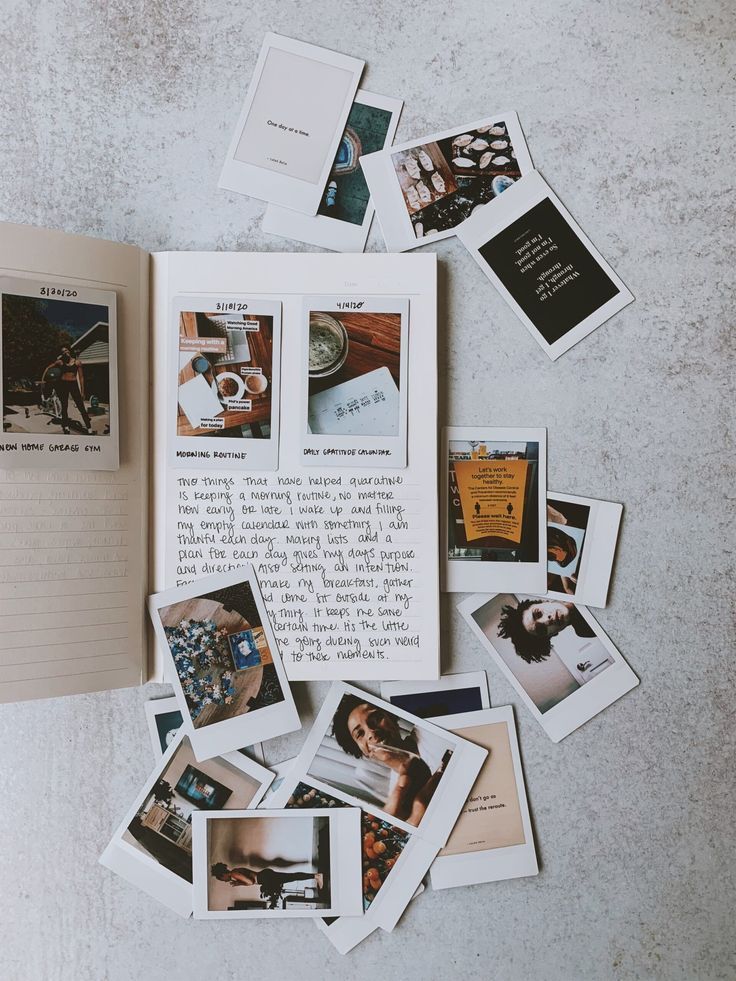 an open book sitting on top of a table filled with pictures and photos next to a notebook