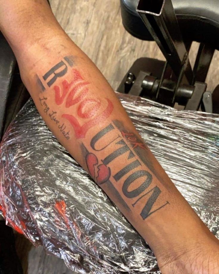 a person with a tattoo on their arm sitting in a chair next to a hair dryer