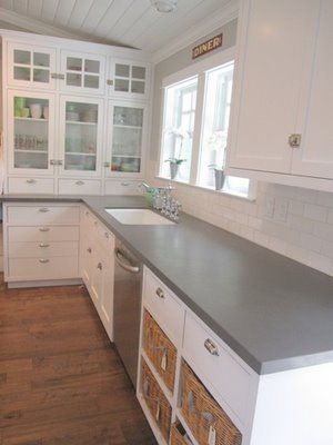 a kitchen with white cabinets and gray counter tops