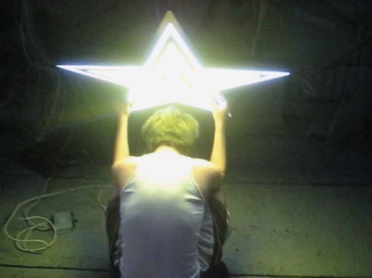 a person sitting on the ground holding up a star shaped object