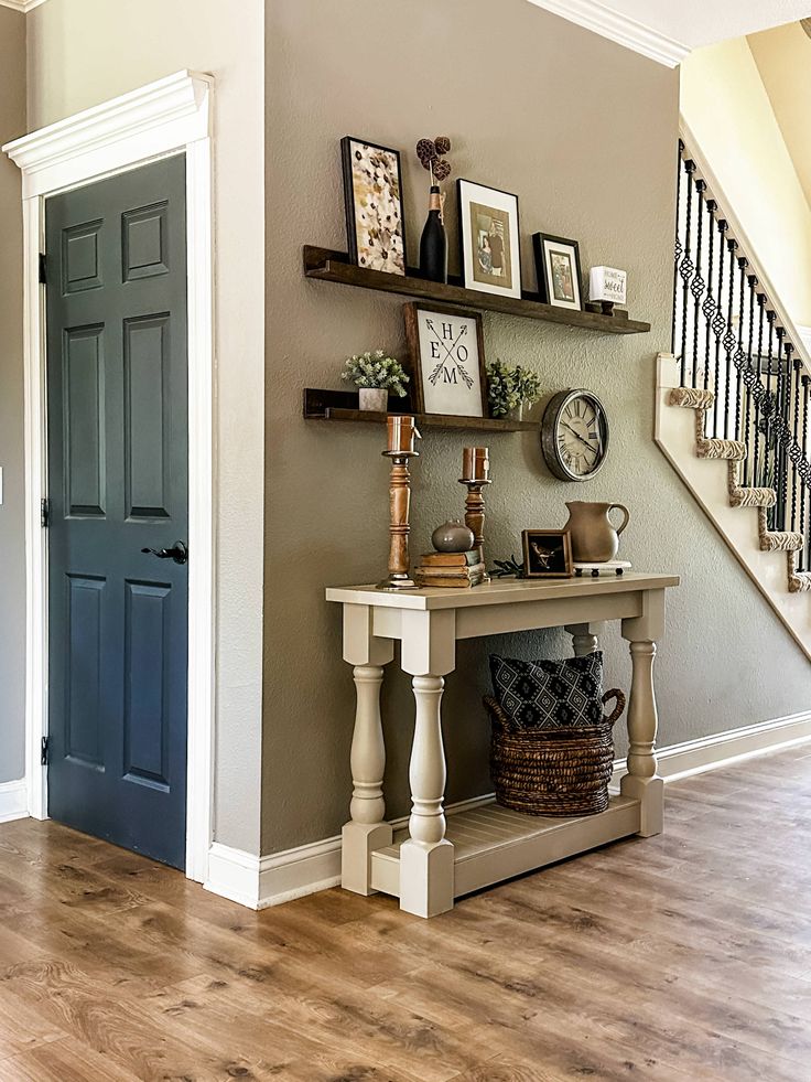 an entryway with shelves and pictures on the wall next to a wooden floor in front of a blue door