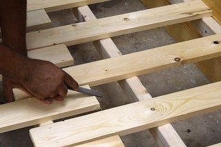 a person cutting wood with a pair of scissors on top of the wooden planks