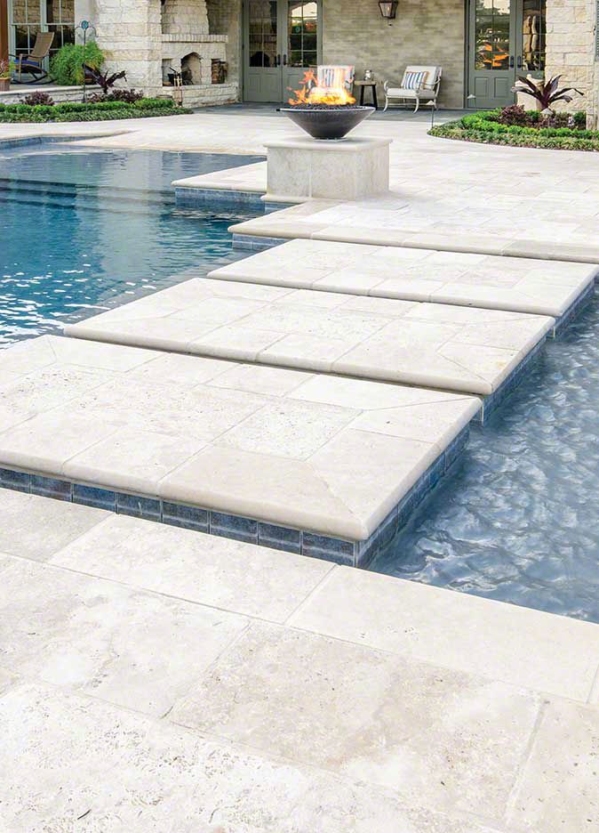 an outdoor pool with steps leading to the fire pit and lounge chairs in the background