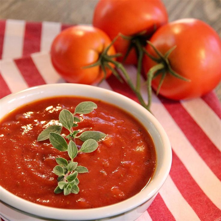 a white bowl filled with tomato sauce and sprigs