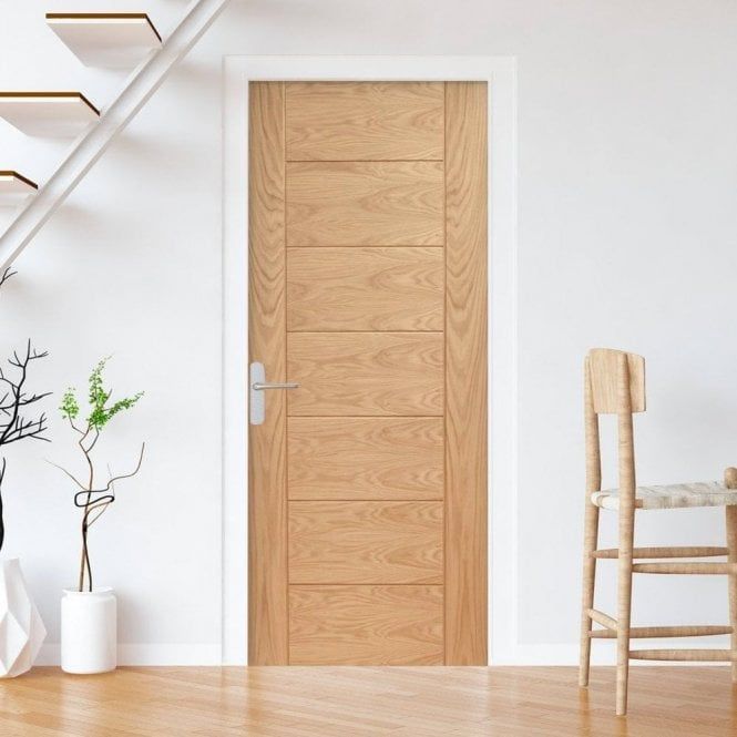 a wooden door sitting next to a white chair in a living room under a stair case