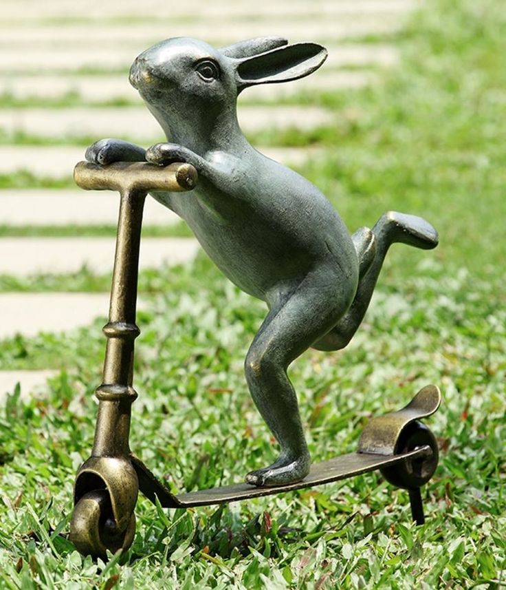 a statue of a dog on a scooter in the grass with its legs spread out