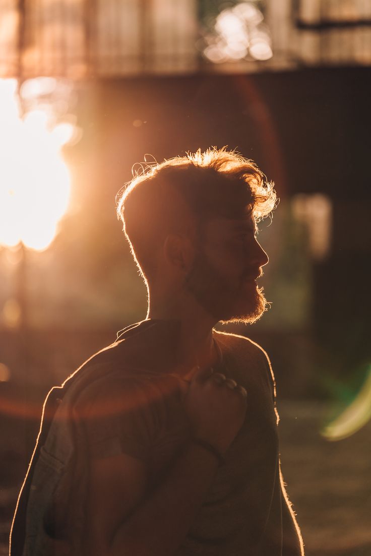 a man standing in front of the sun with his hands on his hips and looking off into the distance