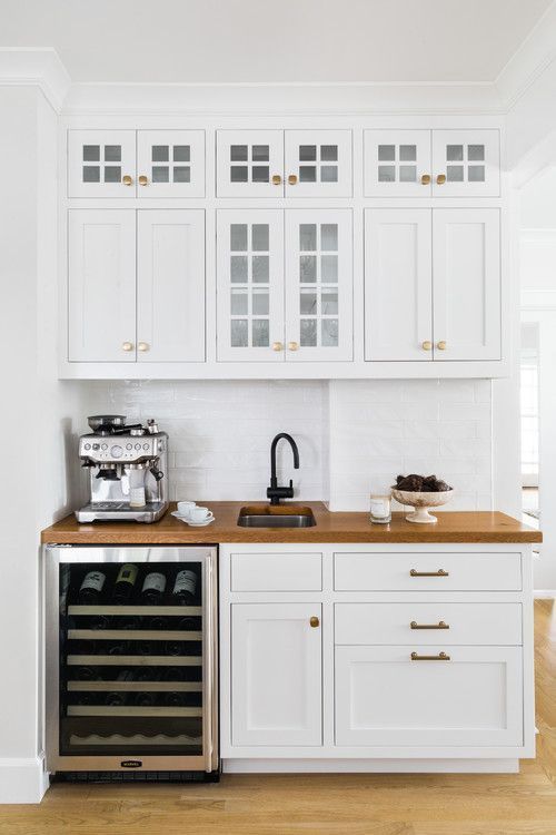 a kitchen with white cabinets and wood counter tops, an appliance for wine