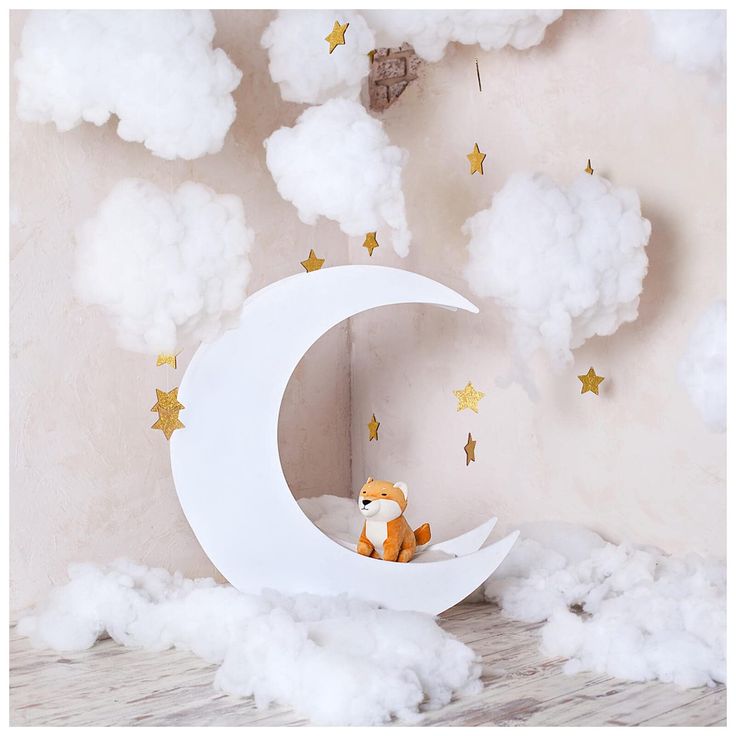 a teddy bear sitting on top of a crescent shaped bed in front of clouds and stars